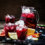 red sangria with fruit and ice in pitcher and glassses
