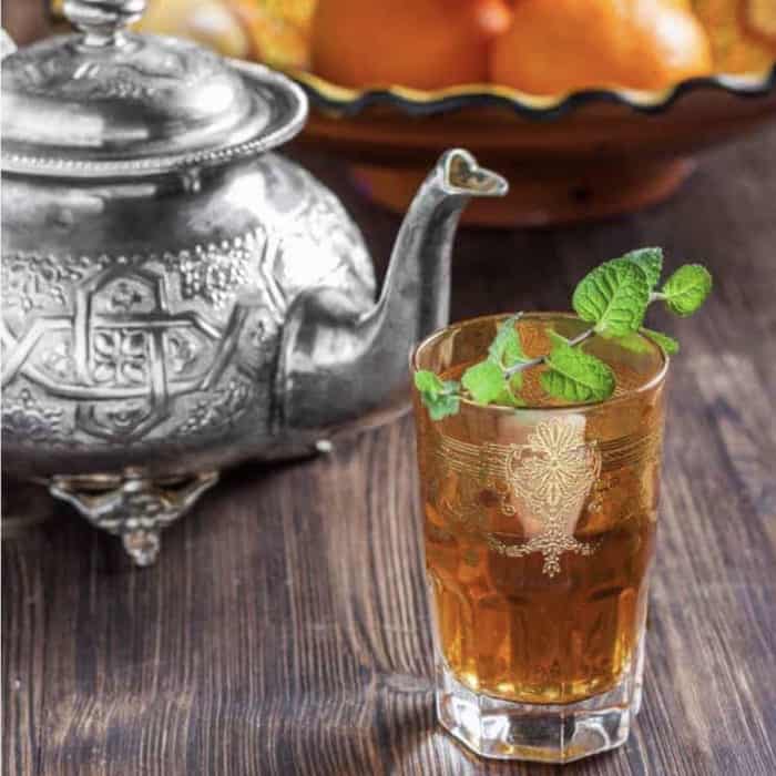 Morrocan mint tea in Turkish tea glass with tea pot in background