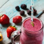Mixed berry smoothie in mason jar with straw
