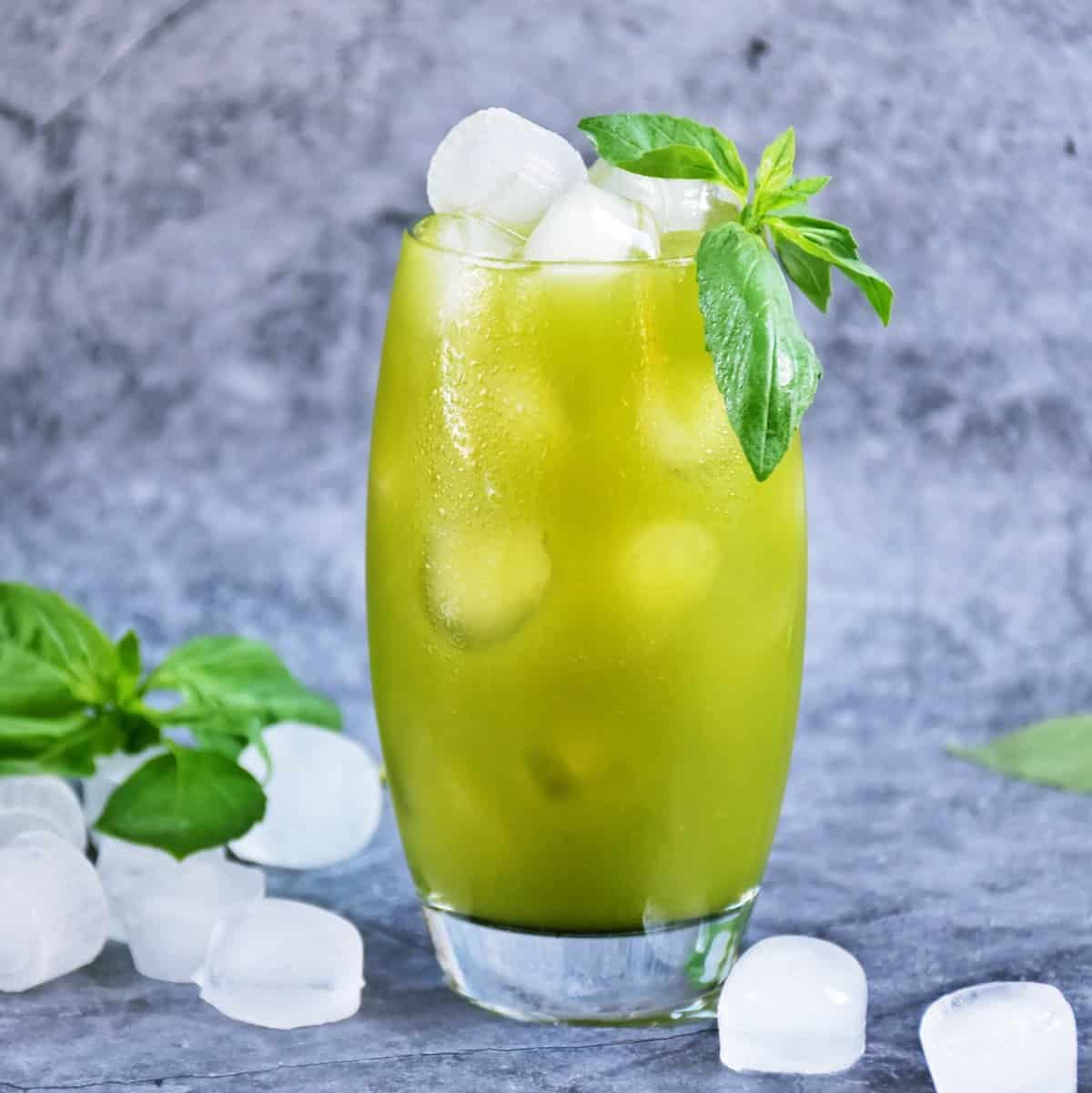 iced matcha lemonade in glass with ice and garnished with basil